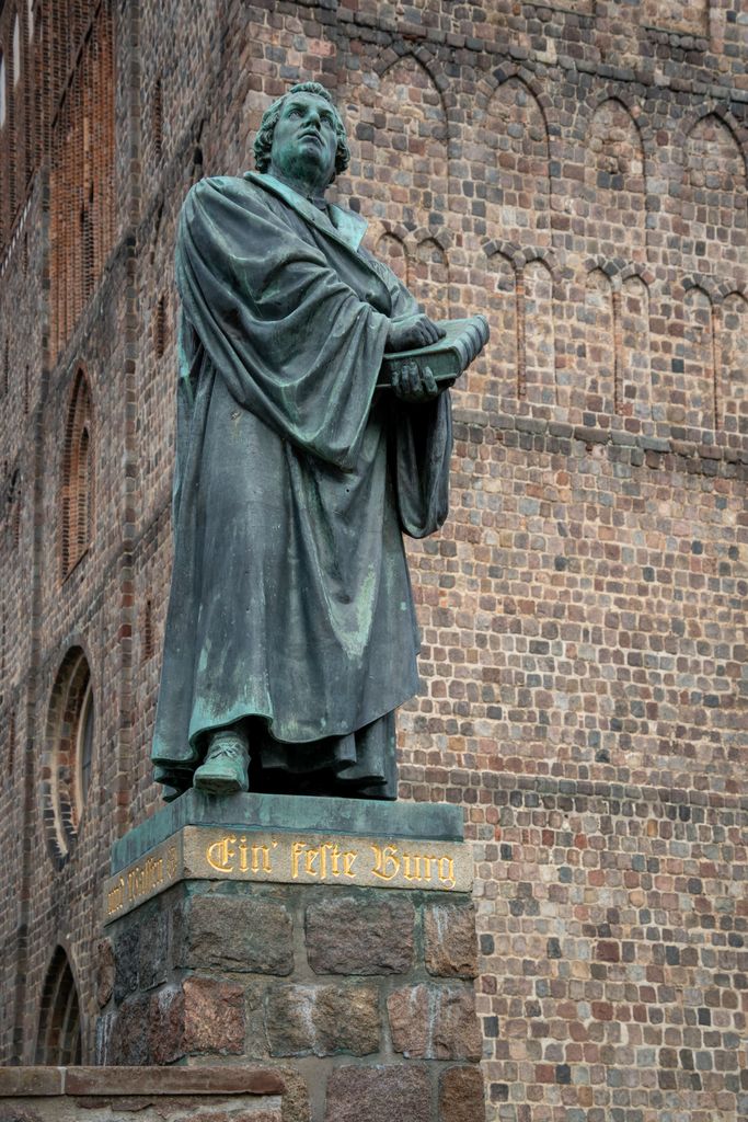 Statue of Martin Luther outside a historic brick church, symbolizing the Protestant Reformation.